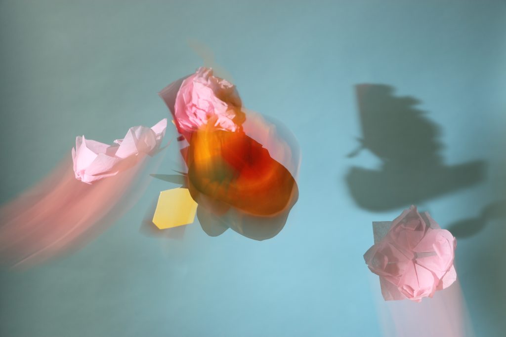 Photograph of paper flowers in the air.