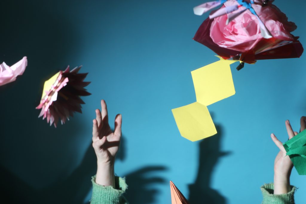 Photograph of coloured paper flowers thrown in the air. Flash photography.