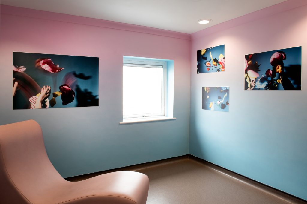 Photo of a room painted blue to pink on the walls with photographs of paper flowers in the air