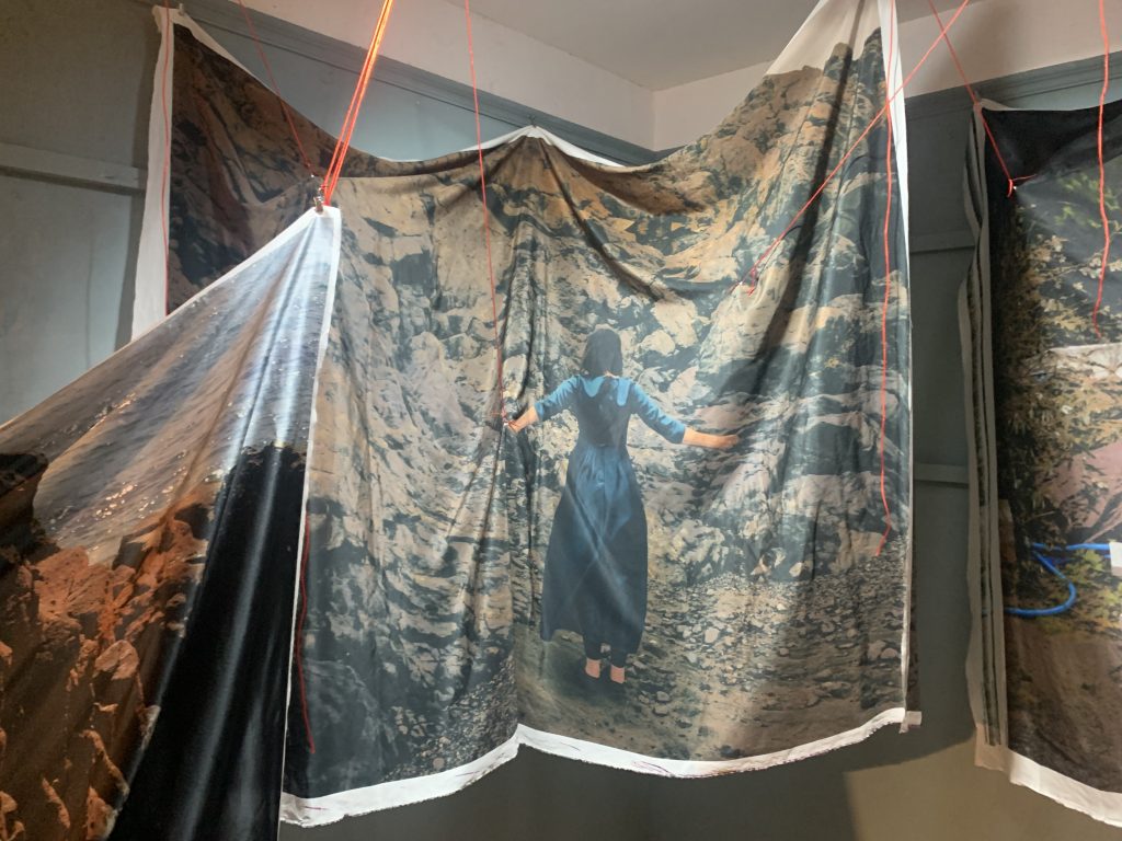 Printed fabric - showing woman sitting on rocks and woman standing at bottom of cliff.