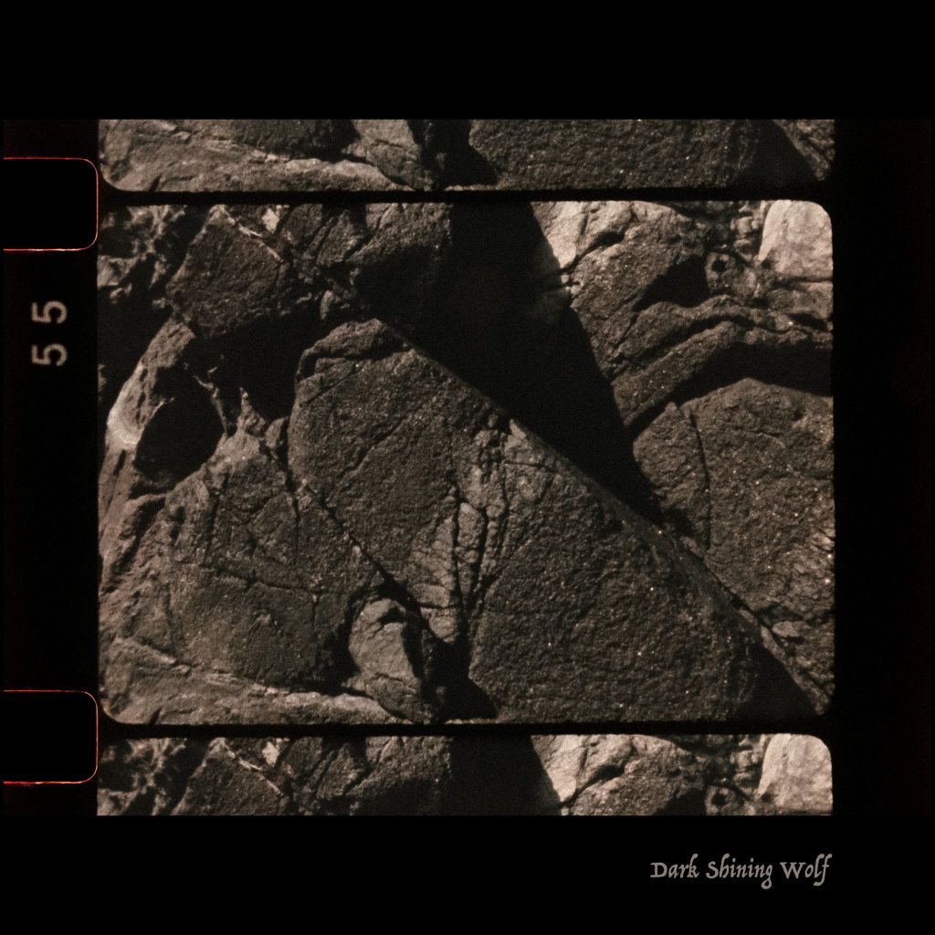 Photograph of a rock with a black border. Dark image with high contrast.