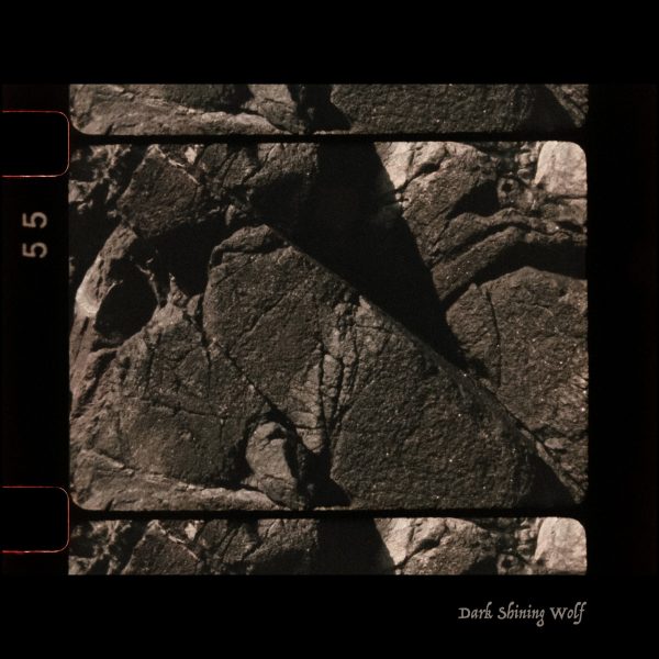 Photograph of a rock with a black border. Dark image with high contrast.