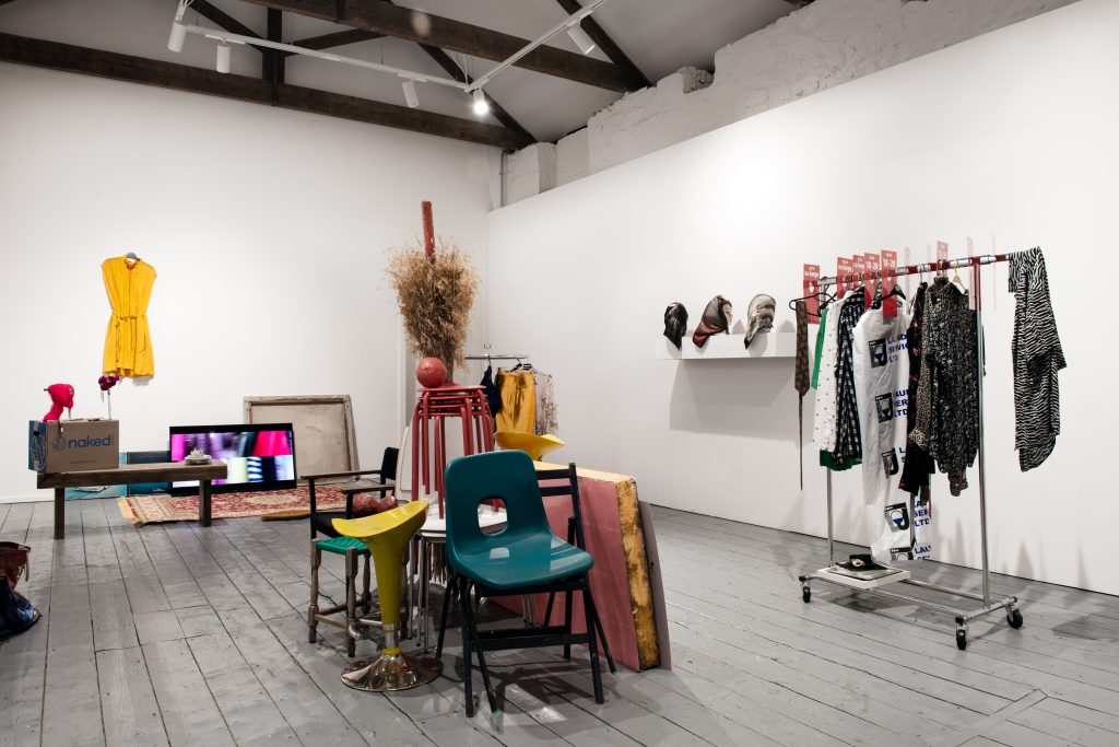 Second Hand Part 2, Auction House installation, clothes and household objects loosely arranged in the gallery, mimicking charity shop displays.