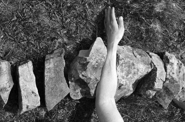 Photograph of an arm lying on rocks